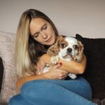 Woman cuddling dog on sofa