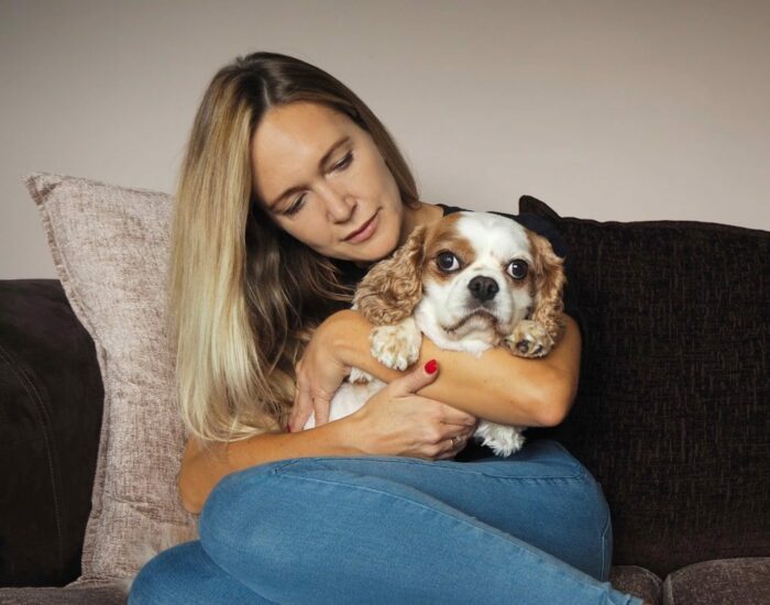 Woman cuddling dog on sofa