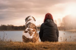 Woman and dog sitting at water's edge