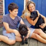 Mother and son holding black dogs