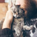 Man kissing a cat in his arms