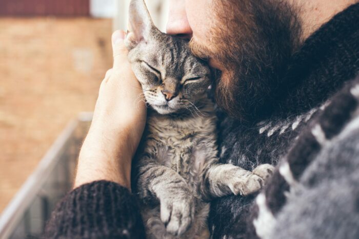 Man kissing a cat in his arms