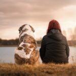 Woman and dog sat by water