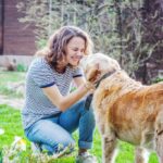 Woman cuddling dog in garden