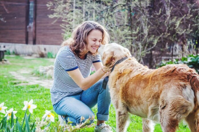 Woman cuddling dog in garden