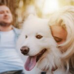 Woman cuddling white dog