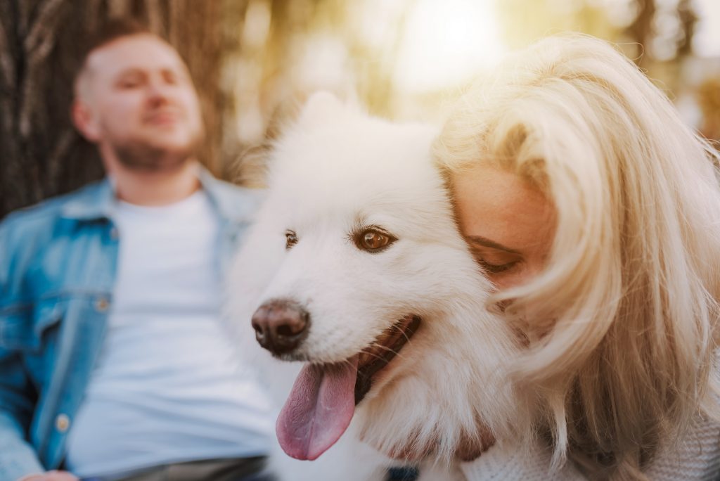 Woman cuddling white dog