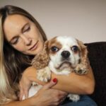 Woman cuddling dog on sofa