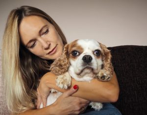 Woman cuddling dog on sofa