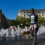 Man walking dog near water fountains