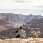 Woman and dog sat facing cliffs