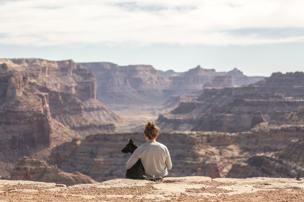 Woman and dog sat facing cliffs