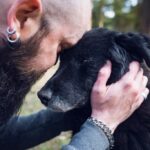 Man cuddling black dog