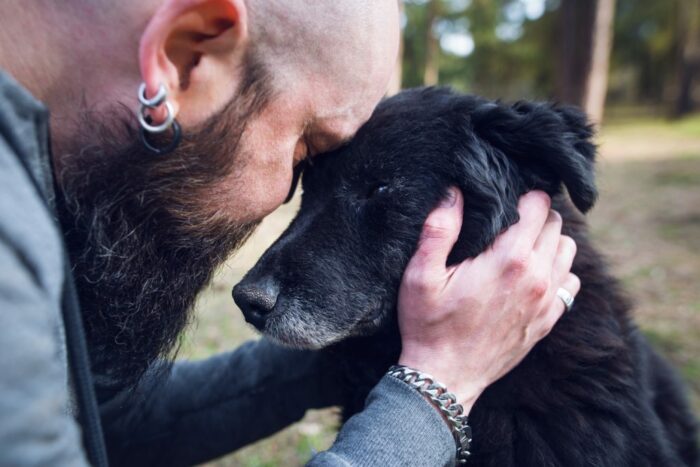 Man cuddling black dog