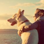 Woman and white dog looking into sunset