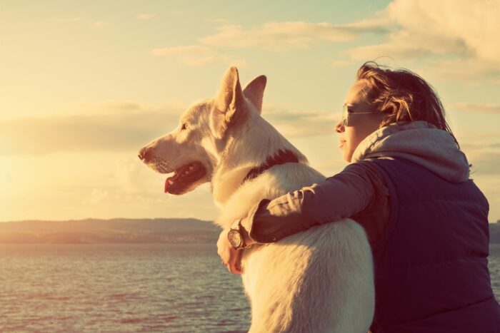 Woman and white dog looking into sunset