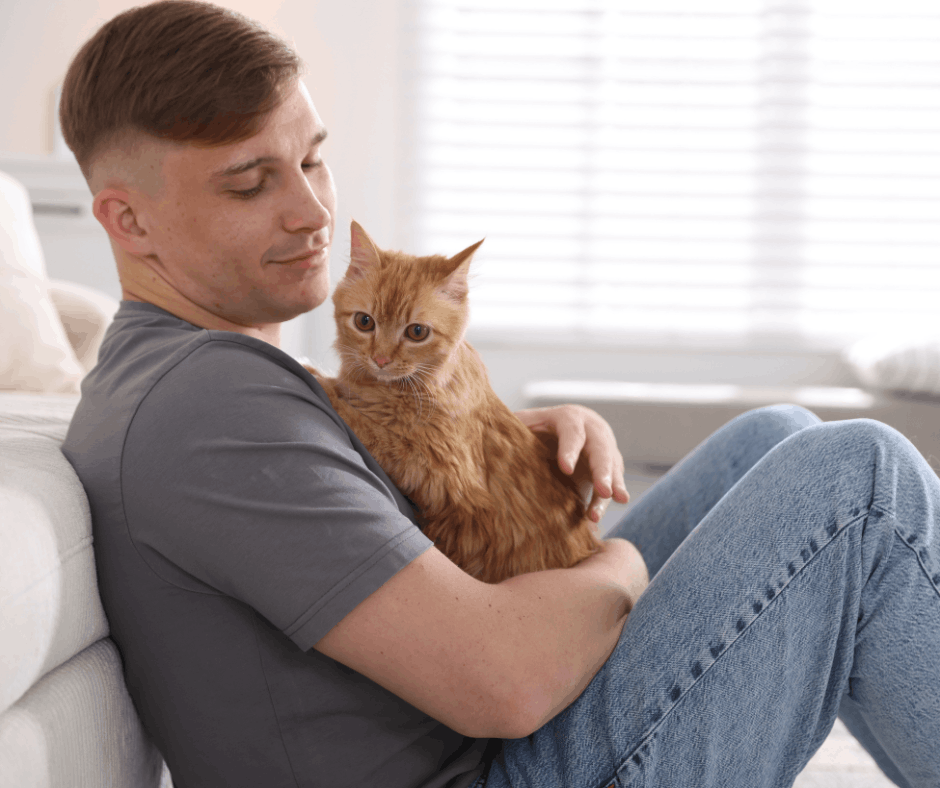 man cuddling ginger cat